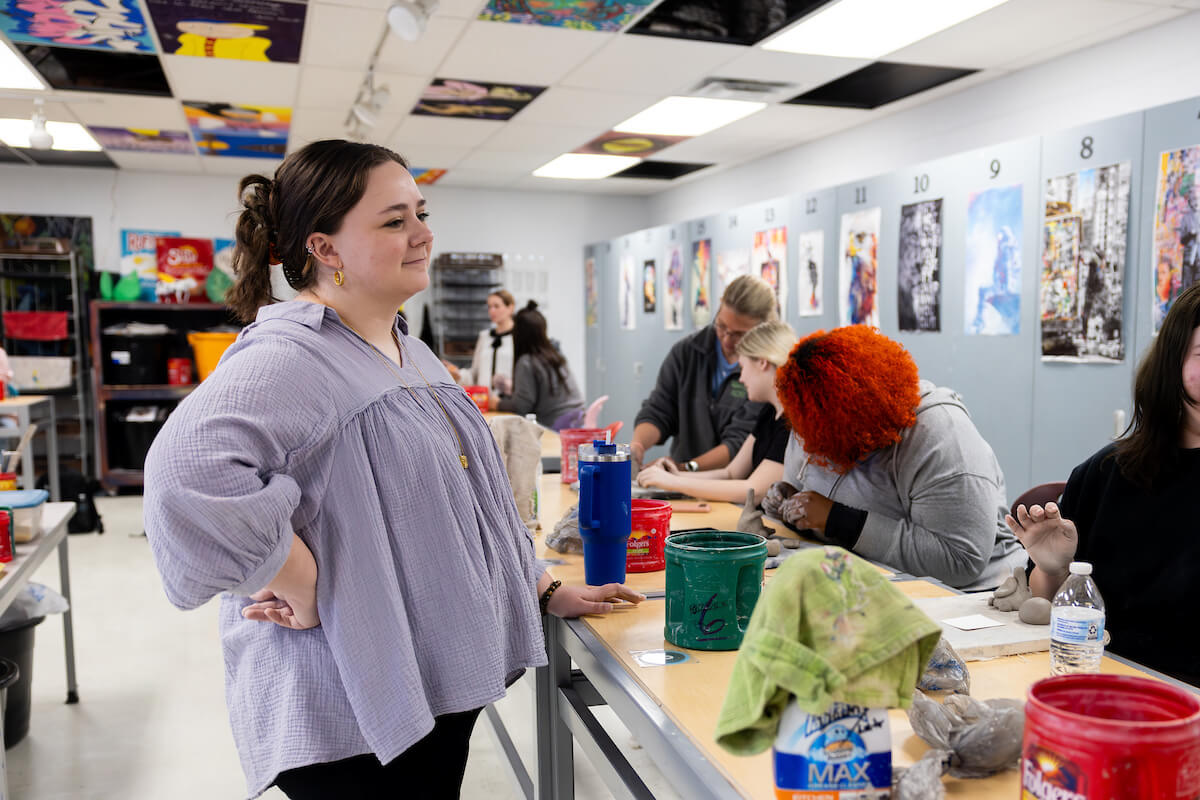 A student teacher observes older students during an art activity